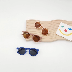 Detailed display of colorful matte round frame sunglasses for kids on a wooden stand
