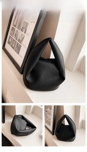 Close-up of black lychee grain leather handbag with minimalist pleated triangle structure