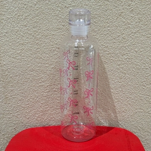 Detail of transparent water bottle featuring pink bow patterns and time markers