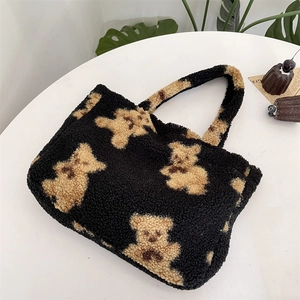 Flat lay of black fuzzy bear tote bag on table with monstera leaf and dessert props