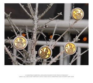 Detail of warm LED Christmas string lights with hollow wooden snowman shapes on snowy branches