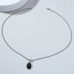 Dettaglio della collana hip-hop con pendente ovale nero e catena in metallo argento