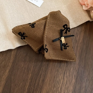 Detail of herringbone fabric hair claw with velvet bow embroidery and gold metal tag
