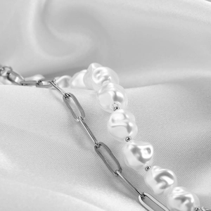 Detail of silver paperclip chain and irregular baroque pearl texture on white silk