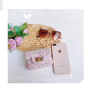 Rosa Tweed Mini Tasche mit Kette neben Handy zum Größenvergleich auf Strohmatte