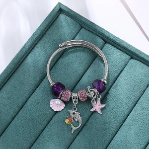Bohemian silver wire bracelet featuring dolphin, seashell, and purple beads in velvet tray