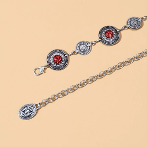 Macro view of vintage silver waist chain with red resin inlay and animal relief coins