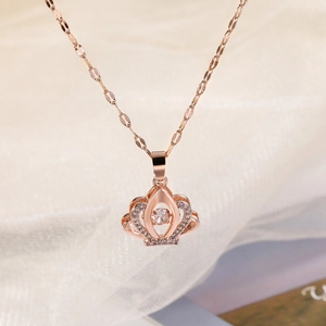 Elegant rose gold crown necklace with a dancing stone pendant on a beige fabric background