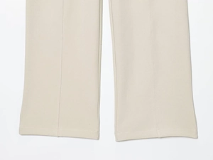 Detail of beige trousers hem showing high-quality stitching and centered crease lines