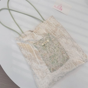 Détail du sac cabas en velours avec poche en dentelle florale et étiquette de marque