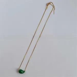 Detail of gold box chain necklace with a glossy green teardrop pendant and adjustable clasp
