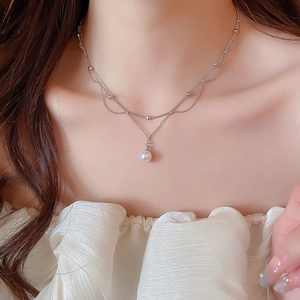 Gros plan d'un collier de perles argenté à deux rangs sur une tenue élégante en dentelle
