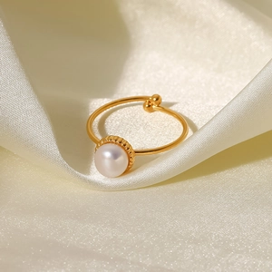 Close-up of 18K gold stainless steel ring with freshwater pearl on silk fabric