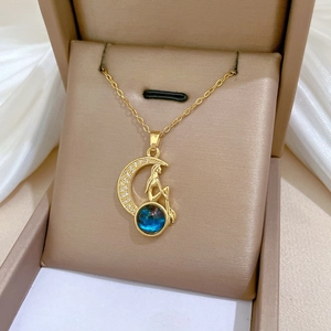 Detailed macro shot of a golden mermaid moon necklace with blue gemstone on silk background