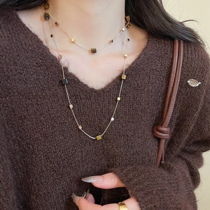 Close-up of double-layered necklace with tiger eye square pendants on a brown sweater