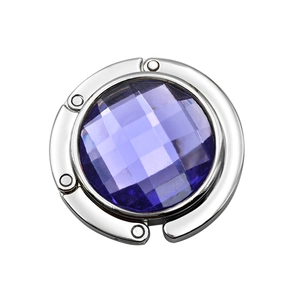Close-up of portable folding handbag hook with faceted purple crystal in silver frame