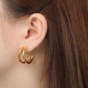 Close-up of double-layered gold hoop earrings worn by a model with polished metal finish