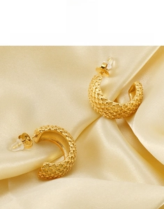 Détails macro des boucles d'oreilles C en plaqué or 18K avec texture de maille sur soie