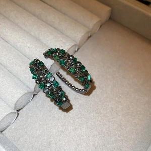 Sparkling C-shaped earrings with green emerald stones and gray crystals in gunmetal finish