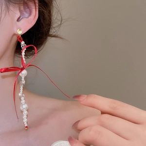 Close-up of pearl tassel bow earrings with red ribbon on model for a sweet style