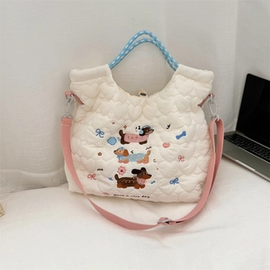 Detail of white quilted handbag with cute dachshund embroidery and blue woven handles