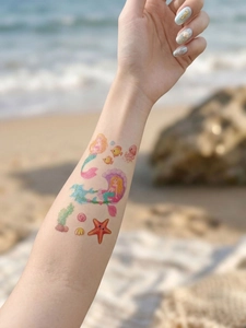 Detail of mermaid and starfish temporary tattoos with glitter finish on a child's arm