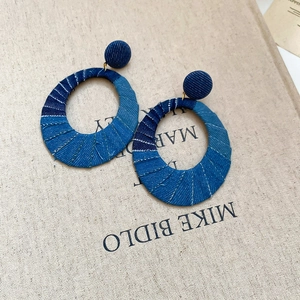 Close-up of denim fabric wrapped oval hoop earrings with vintage patchwork texture