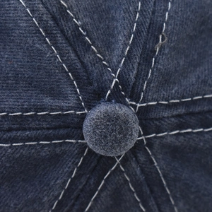 Vue macro du haut d'une casquette en coton délavé bleu marine avec coutures blanches contrastées