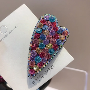 Close-up of heart-shaped hair clip with multi-colored crystals on fashion jewelry card