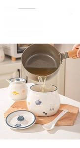 Detail of pouring hot oil into a cream ceramic lard jar with lid and matching spoon