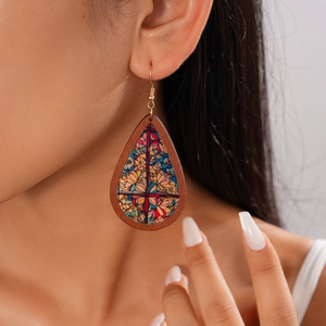 Detail of bohemian teardrop wood earring with colorful stained glass print on a model
