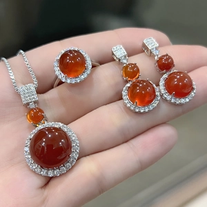 Detail shot of round orange chalcedony jewelry set including necklace, ring, and earrings