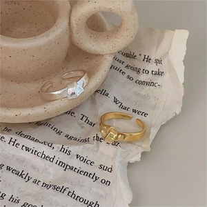 Close-up of gold and silver knot rings on aesthetic beige ceramic and book background