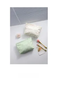 Close-up of jacquard floral lace makeup bags in mint green and cream white with zipper