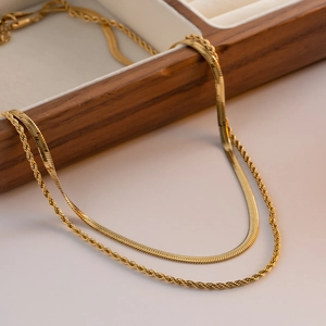 Close-up of golden double-layer necklace with snake and twisted chains on wooden box