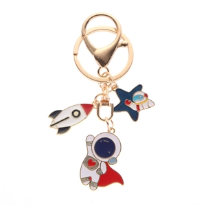 Golden astronaut metal keychain featuring enamel rocket and star charms on white background