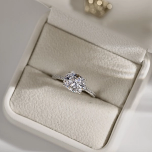 Macro shot of a brilliant round-cut diamond ring presented in a beige velvet luxury gift box
