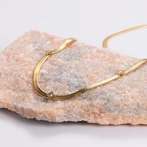 Elegant gold snake bone chain necklace with sparkling zircon square pendants on stone