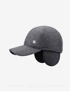 Detail of dark grey wool baseball cap showing side metal logo and fold-down ear protection
