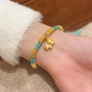 Close-up of woven blue and green rope bracelet with golden unicorn charm and enamel detail