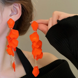 Detail of vibrant orange resin flower petal tassel earrings worn by a model