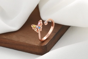 Detail of rose gold butterfly ring with colorful zircons on a rustic wooden surface