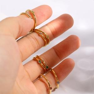 Detail of stacked gold gemstone rings showing colorful stones and minimalist design