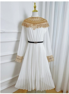 Close-up of white pleated dress with golden sequin embroidery on neck and sleeves