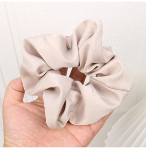 Detailed close-up of champagne satin scrunchie showing large pleated fabric texture