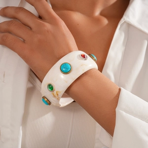 Detail of wide resin bangle with marble texture and colorful gemstones on female model