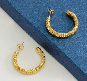 Close-up of golden C-shaped hoop earrings with twisted rope texture on a navy display box