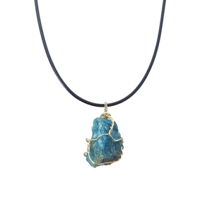 Detail of blue raw crystal stone pendant wrapped in golden wire on black cord