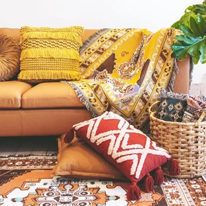 Detail of bohemian knit blanket and tasseled pillows with geometric patterns on a sofa