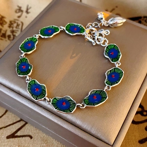 Detail of silver enamel lotus pod bracelet with floral charm in luxury jewelry box
